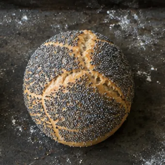 Rundes Brötchen mit dunklem Mohn