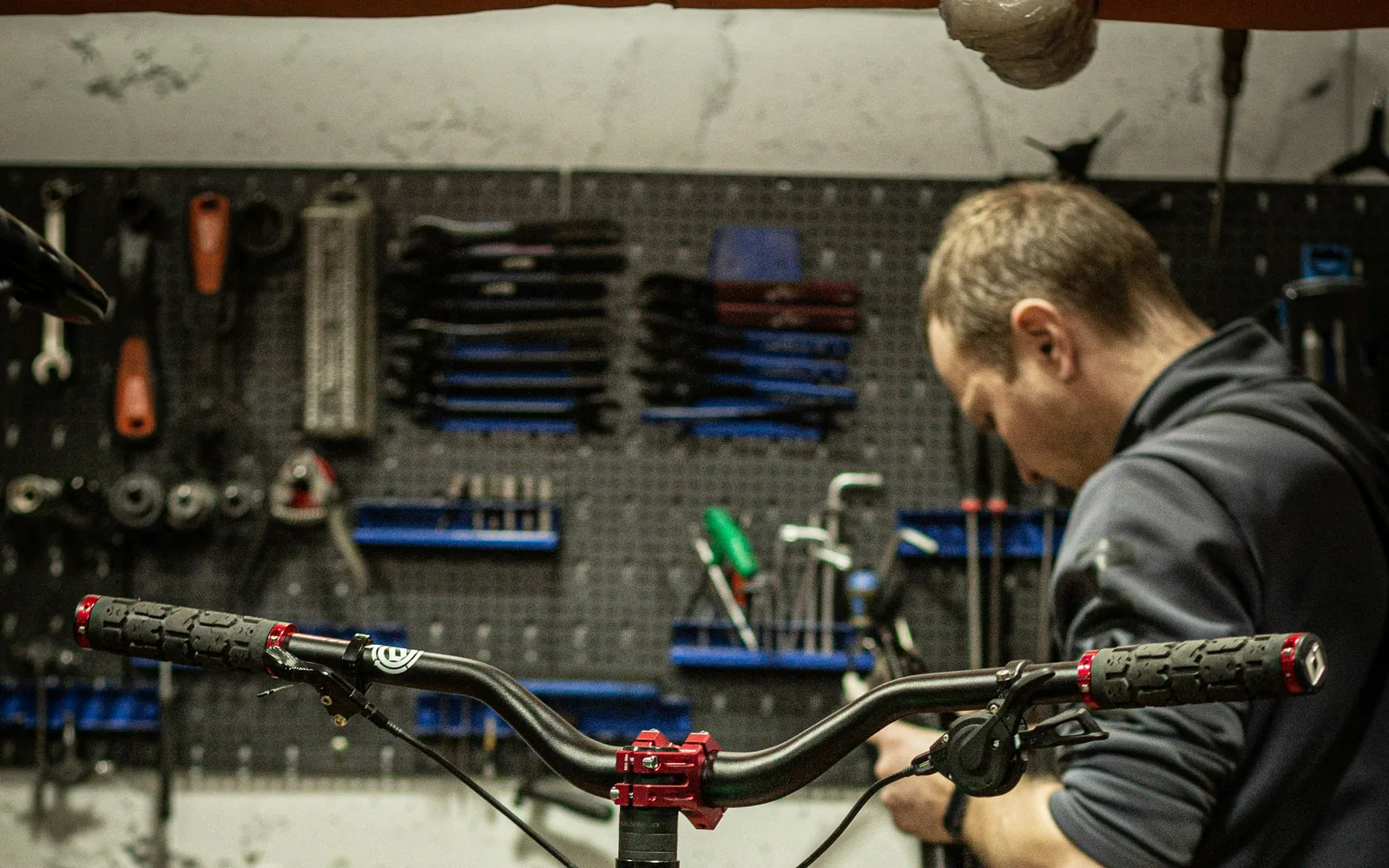 Blick in die Werkstatt: ein Mechaniker stellt an einem Rad im Montageständer den Lenker ein.