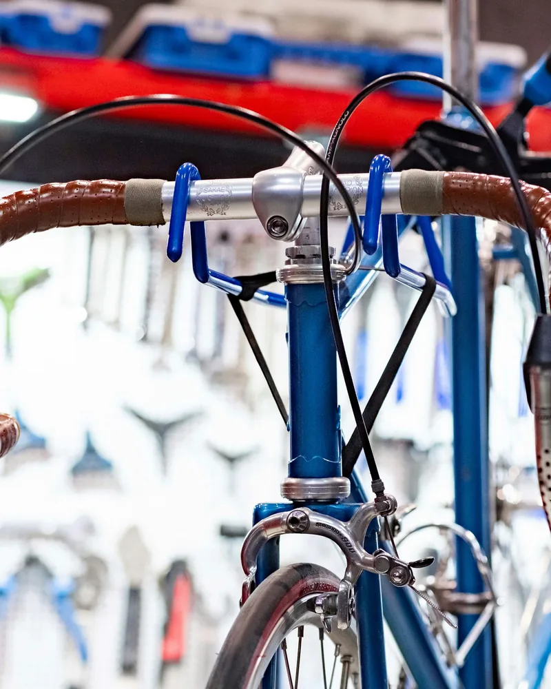 Ein Rennrad mit braunem Lenkerband hängt im Montageständer vor der Werkzeugwand.