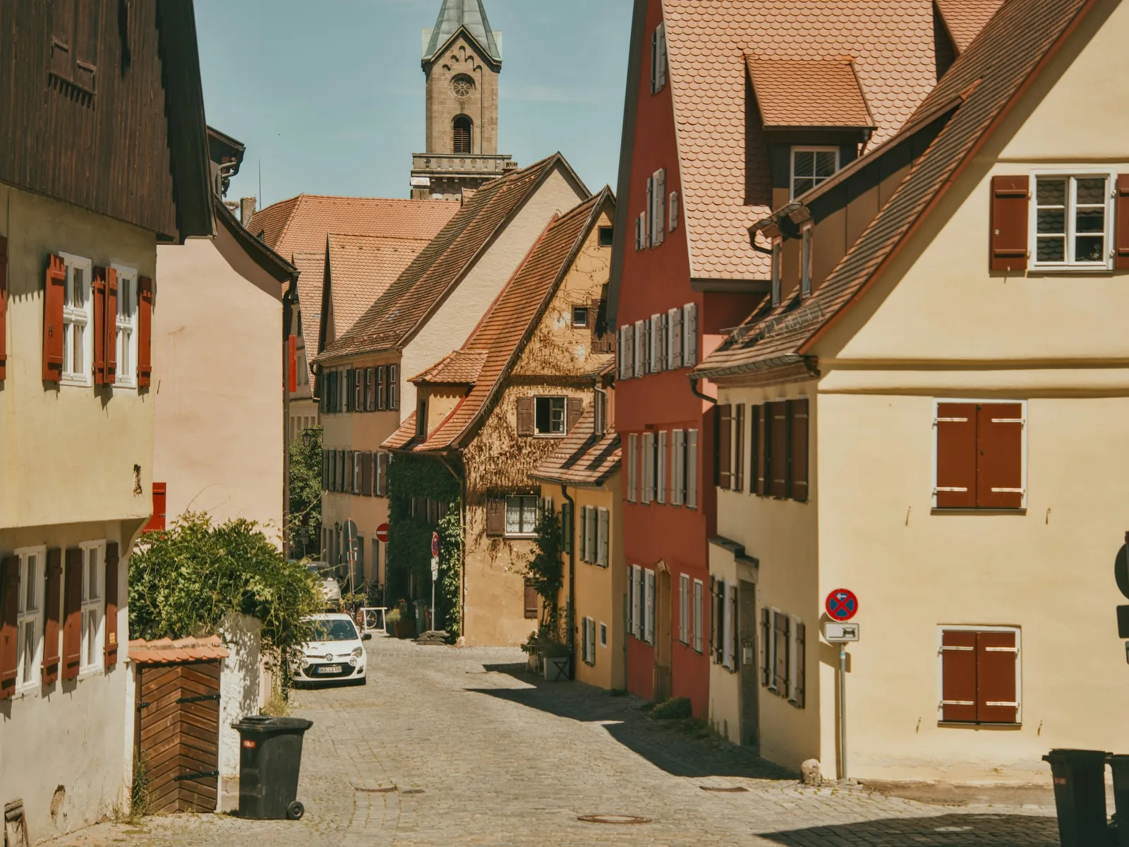 Kopfsteingepflasterte Altstadtstraße mit Kirchturm über den Dächern