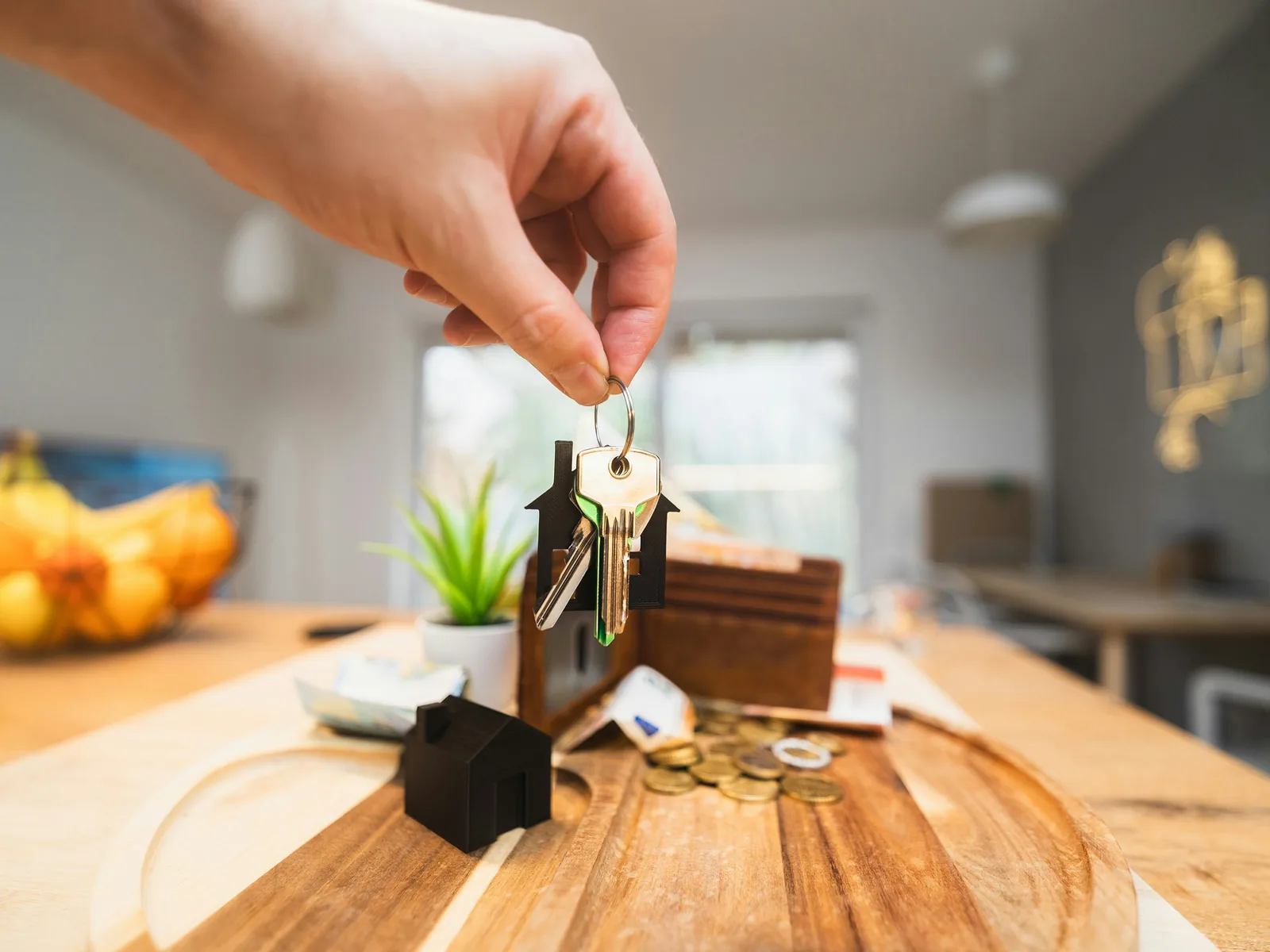 Hand mit Hausschlüssel über einem Holztisch in einer Wohnung