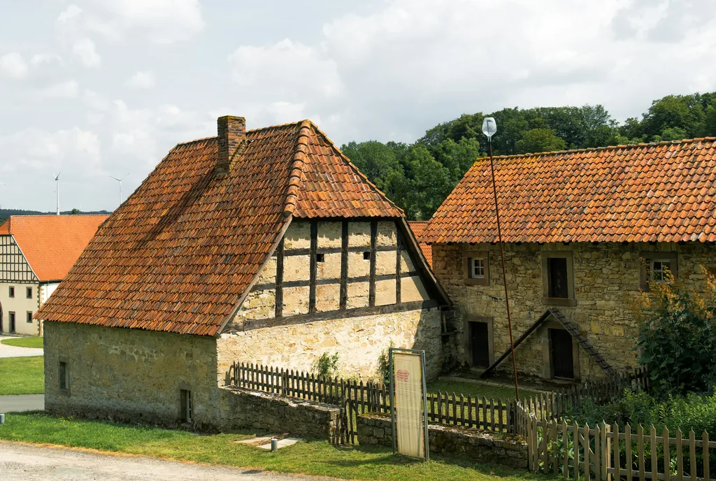 Bruchsteinhaus mit Fachwerkscheune, Ziegeldächern und Holzzaun
